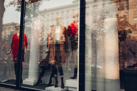 Manikins dressed in autumn outfits on showcase of a store in city center. Shopping and sales concept. Black fridayの写真素材