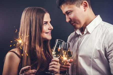Couple celebrating New Year's eve drinking champagne and lighting up sparklers on the partyの写真素材