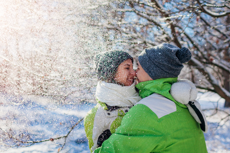 Couple in love throwing snow and hugging in winter forest. Young people having fun during holidaysの写真素材