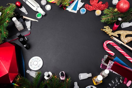 Nail art accessories Christmas sale. Manicure products shopping. Gel polish, uv lamp, remover, rhinestones, foil on black background with New year decorationの写真素材