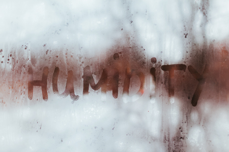 Humidity word written on wet window with condensate. High level of dampness in apartment.の写真素材