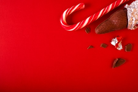 Christmas traditional sweets on red background. Chocolate Santa Clauses with candy cane. Copy spaceの写真素材