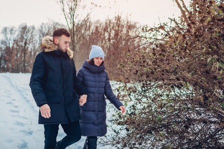 Beautiful loving couple walking in winter forest together. Happy people having fun outdoorsの写真素材