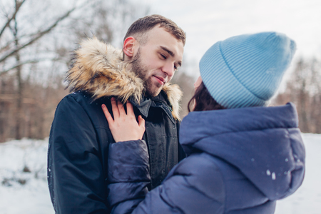 Beautiful loving couple walking and hugging in winter forest. People having fun and chilling outdoorsの写真素材