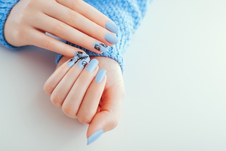 Beautiful New Year manicure. Blue nails with black design and rhinestones. Body care concept. Space