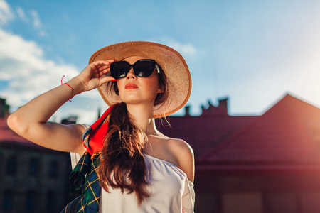 Young stylish woman wearing hat and sunglasses outdoors. Stylish girl with backpack walking in Lvivの写真素材