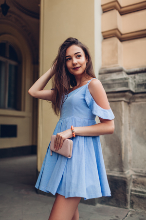 Outdoor portrait of young beautiful woman wearing stylish spring outfit and holding purse. Fashion, beauty model in cityの写真素材