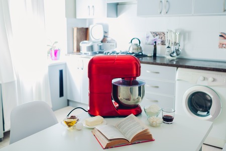 Happy housewife with multicooker and other culinary appliances at homeの写真素材