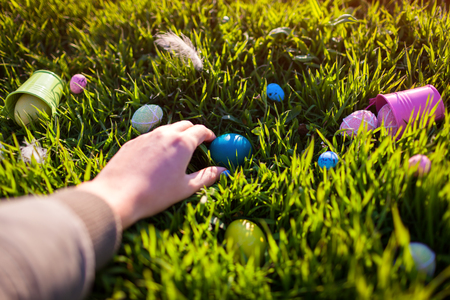 Happy Easter. Easter eggs hidden in spring grass. Woman holding holiday egg