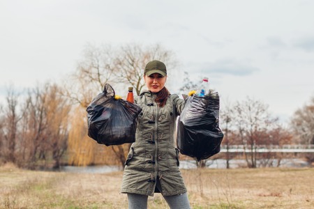 Woman volunteer cleaned up the trash in park. People picked up garbage and showing result with full bags. Ecology and environment concept. Challengeの写真素材