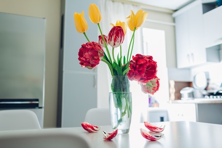 Modern kitchen design. Interior of white and silver kitchen decorated with flowers. Bouquet of fresh tulipsの写真素材