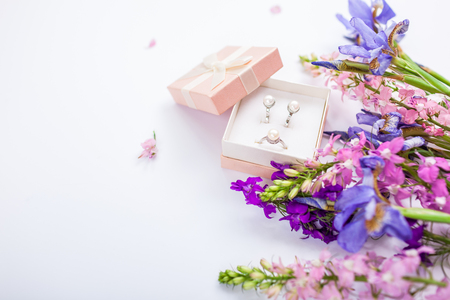 Set of silver ring and earrings with pearls in the gift box with purple irises. Present for holiday with flowersの写真素材