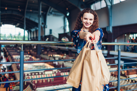 Young happy woman holding shopping paper bags in shopping center. Purchasesの写真素材