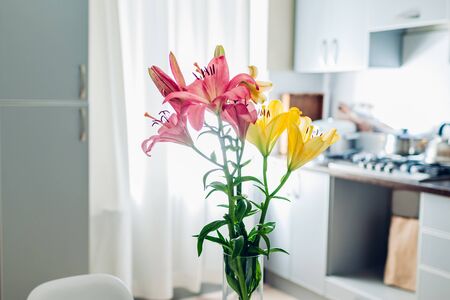 Colorful lilies. Modern kitchen design. Interior of white and silver kitchen decorated with bouquet of fresh flowers.の写真素材