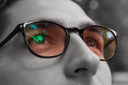 Young man gets colorful bright sight wearing glasses. Eyewear to improve vision. Black and white. Close up of eyesの写真素材