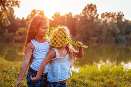 Little girl playing badminton with sister in summer park. Kids having fun outdoors. Close up of shuttlecock and racketの写真素材
