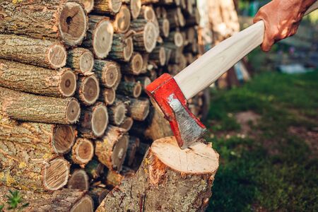 Senior man chopping firewood with an axe in countryside yard. Farmer working outdoors