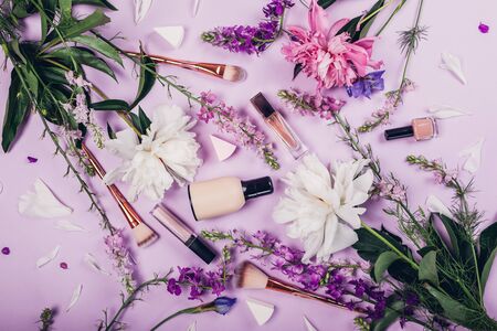 Set of natural cosmetics and brushes with fresh flowers on purple background. Organic cosmetics conceptの写真素材