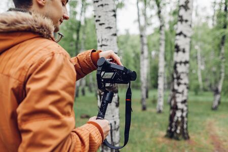 Videographer filming spring forest. Man using steadicam and camera to make footage. Video shoot. Digital devices for video shootの写真素材