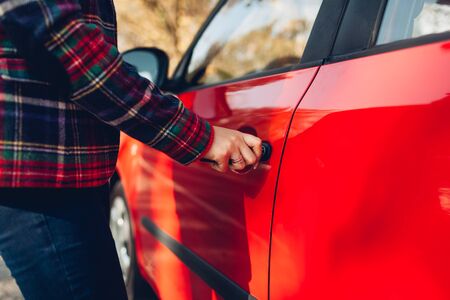 Opening car door. Woman opens red car with key on autumn road