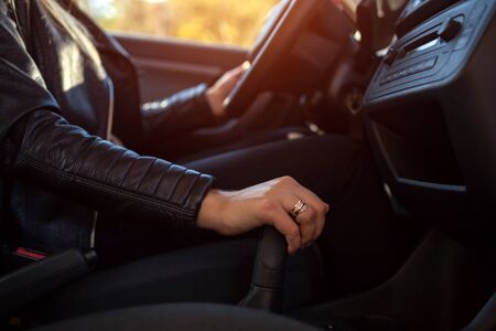 Woman driving. Driver holding hand on transmission and steering wheel. Owner starting her car....