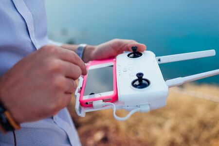 Drone remote control. Man holding copter controller with smartphone. Aerial video shooting