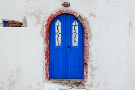Typical architecture in Akrotiri village on Santorini island, Greece. White houses with blue doors....