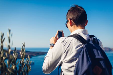 Woman traveler looking at Caldera from Fira or Thera, Santorini island, Greece. Tourist admiring Aegean sea landscape. Tourism, traveling, vacation concept.の写真素材