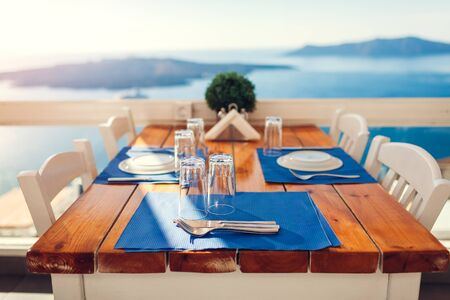 Romantic honeymoon dinner table served on Santorini island, Greece with seaside and mountains landscape, volcano view. Empty cafeの写真素材