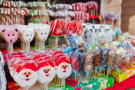 Christmas and New year's street fair sweet food. Santa Claus shaped candies, lollypops and candy canes sold in outdoor shopの写真素材