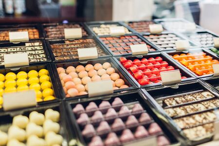 Assortment of chocolate colorful candies desserts on cafe showcase. Variety of sweets with different flavours nuts spices in store. Confectioneryの写真素材