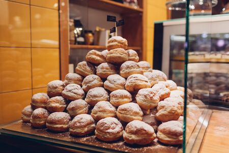 Heap of doughnuts on cafe showcase. Pile of desserts with sugar powder on shelf in store. Restaurant...