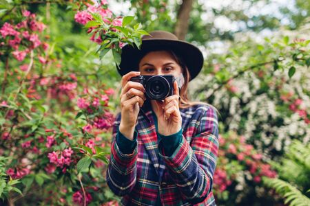 Woman photographer shooting pictures on digital camera in summer garden wearing protective mask.の写真素材