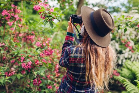 Woman photographing flowers on digital camera in summer garden.の写真素材