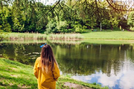 Young woman in yellow raincoat walking in summer park.の写真素材