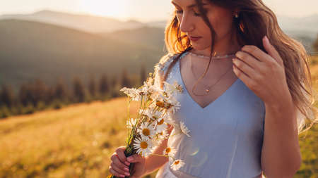 Beautiful bride wearing blue wedding dress in mountains at sunset. Young woman enjoys summer Carpathians landscape holding bouquet of flowers. Back viewの写真素材