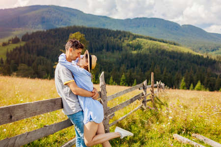 Couple of travelers walking by fence in Carpathian mountains enjoying landscape. People in love hug. Summer vacationの写真素材
