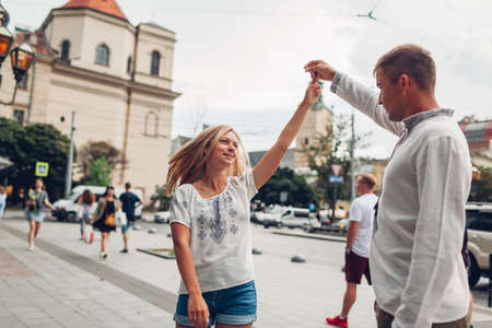 Young people in love walking in old Lviv city center wearing traditional ukrainian shirts. Couple dances having funの写真素材