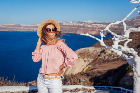 Traveler woman walking on Santorini island, Greece enjoying landscape. Happy girl enjoys seaside Caldera view. Tourismの写真素材