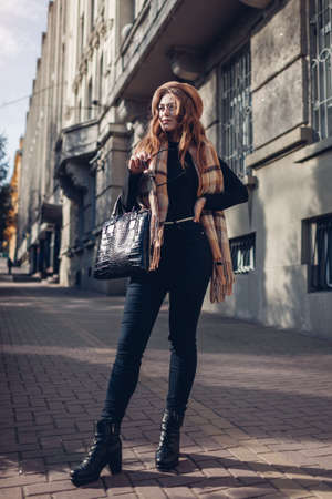 Female fashion. Stylish woman wearing beret, sunglasses and scarf. Spring accessories. Portrait of young girl on city street outdoorsの写真素材