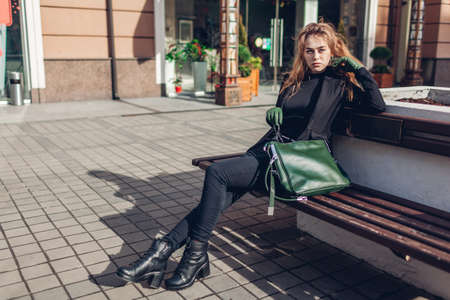 Fashionable woman relaxing outdoors in city. Autumn stylish clothes, shoes, accessories.の写真素材