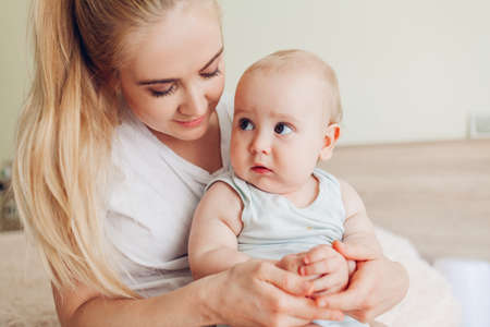 Woman sitting on bed with her newborn baby son. Mother hugging kid. Family relaxing at home. Mothers dayの写真素材
