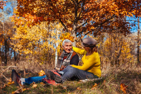 Autumn season walk. Senior couple sitting in park. Man and woman relaxing outdoors having funの写真素材