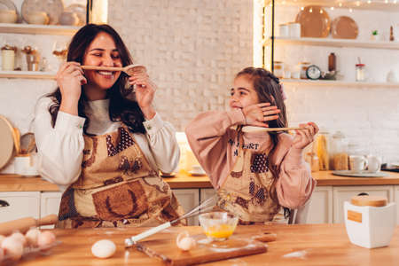 Family having fun with kitchen appliances cooking food for Christmas at home. Mother and daughter laughingの写真素材