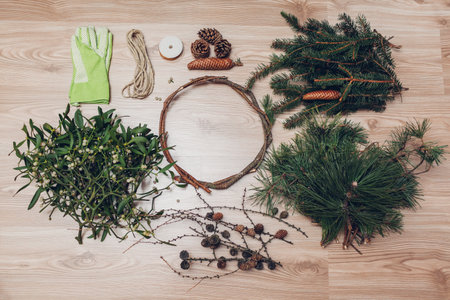 Making Christmas and New Year wreath. Fir, pine, mistletoe branches, cones, wire, rope and gloves prepared. Eco and natural home decorationの写真素材