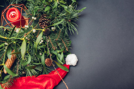 Christmas and New Year wreath made of fir, pine, mistletoe branches, cones with burning candle inside and Santa's hat. Eco and natural home decorationの写真素材