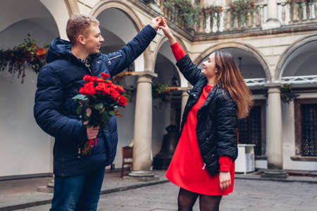 Valentines day romantic date. Boyfriend and girlfriend dancing. Couple walking in italian yard in Lviv with rosesの写真素材