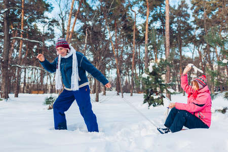 Senior couple sledding. Man carrying his wife on sleigh. Family having fun in winter park. Outdoor activitiesの写真素材