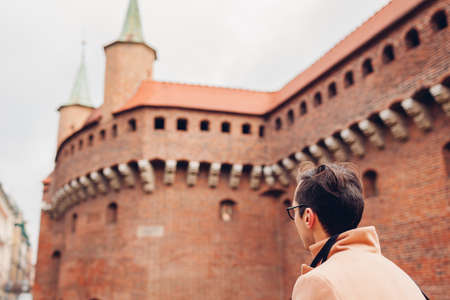Tourist looking at Barbikan gate in Krakow city, Poland. Barbakan museum. Man traveler enjoys...