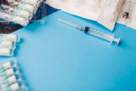 Covid-19 corona cirus 2019-ncov vaccine bottles with syringes. Vaccination, treatment of infection during pandemic. Top view of medicine for injection on blue backgroundの写真素材